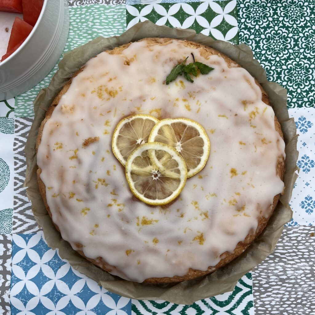 Glutenfreier Zitronenkuchen, schön dekoriert mit echten Zitronenscheiben, rund, auf Tisch