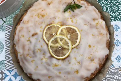 Glutenfreier Zitronenkuchen, schön dekoriert mit echten Zitronenscheiben, rund, auf Tisch