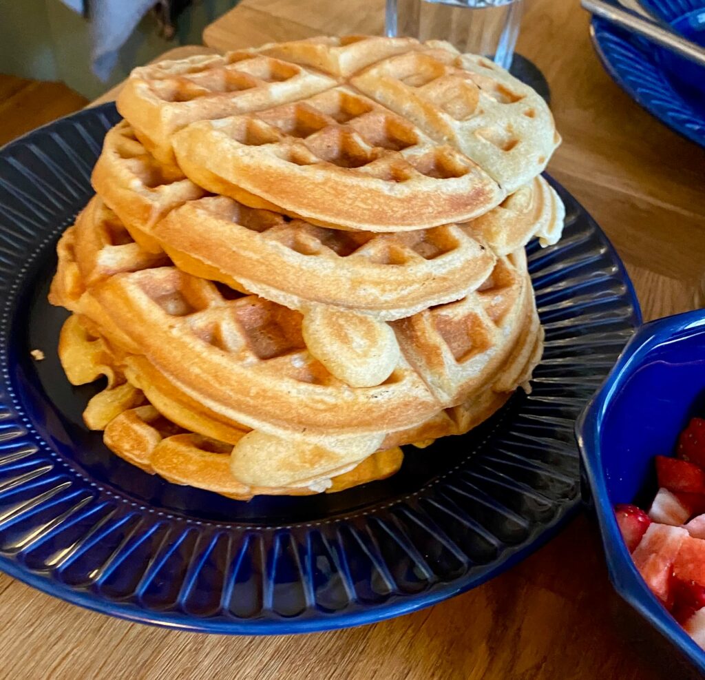 Turm glutenfreier Waffeln auf blauem Teller.