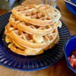 Turm glutenfreier Waffeln auf blauem Teller.