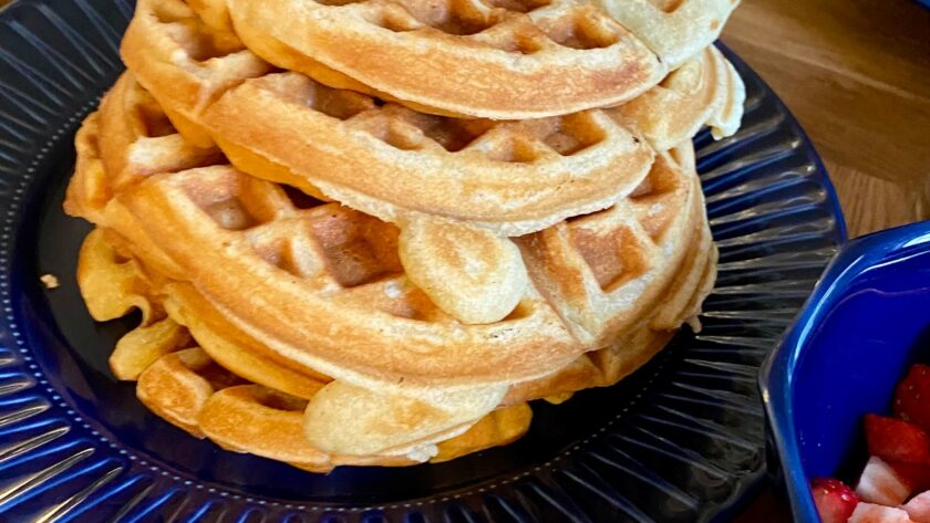 Turm glutenfreier Waffeln auf blauem Teller.