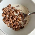 Glutenfreies Müsli in einer Schale mit Milch und Löffel.