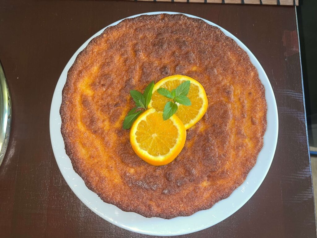 Glutenfreier Orangenkuchen aus ganzen Orangen, dekoriert mit Minze auf Teller.