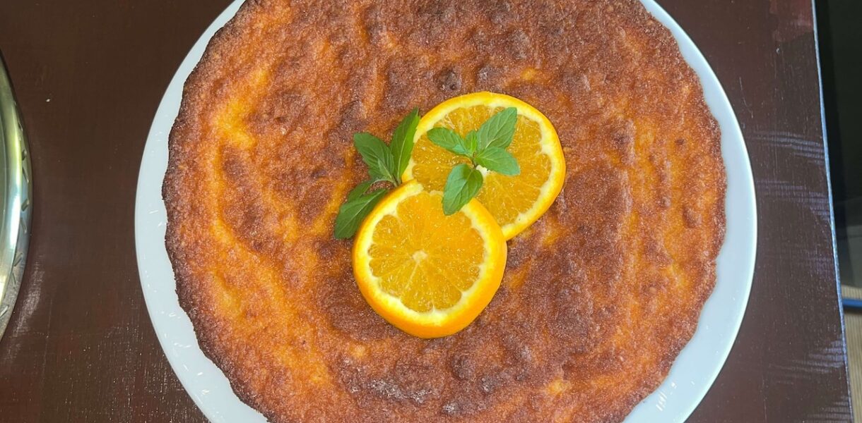 Glutenfreier Orangenkuchen aus ganzen Orangen, dekoriert mit Minze auf Teller.