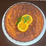 Glutenfreier Orangenkuchen aus ganzen Orangen, dekoriert mit Minze auf Teller.