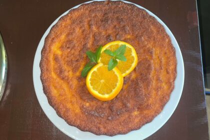 Glutenfreier Orangenkuchen aus ganzen Orangen, dekoriert mit Minze auf Teller.