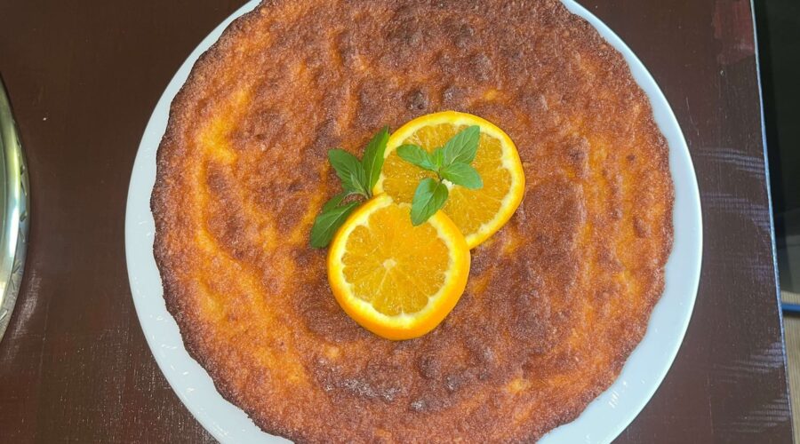 Glutenfreier Orangenkuchen aus ganzen Orangen, dekoriert mit Minze auf Teller.